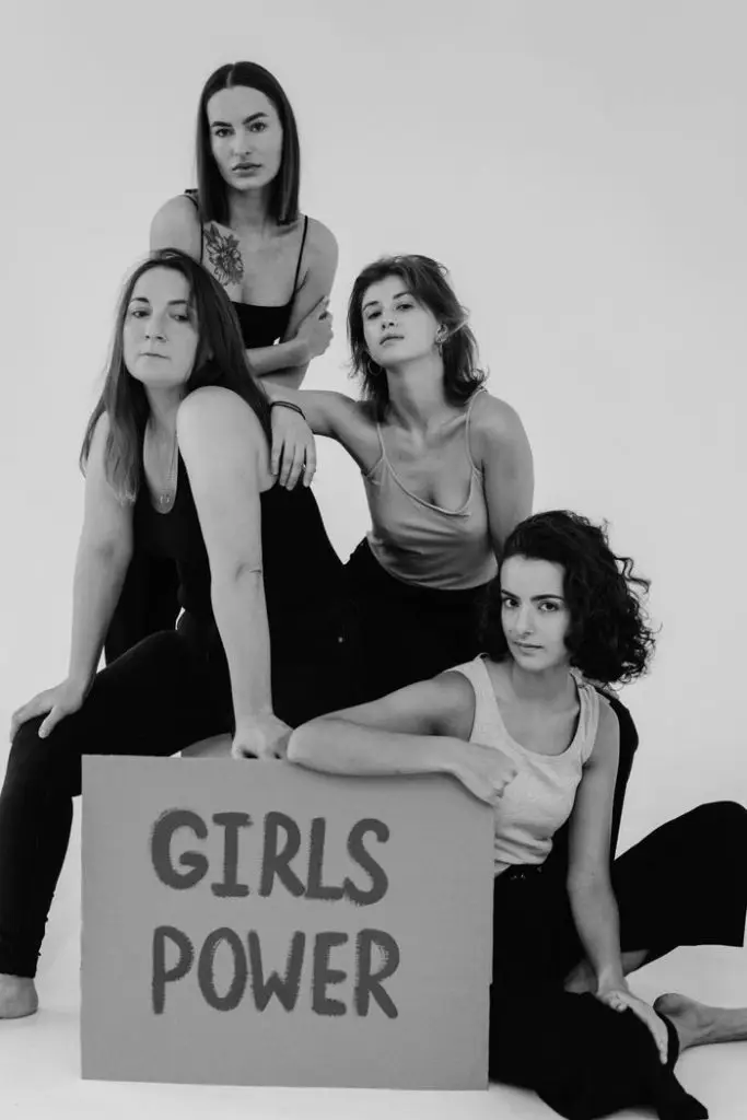 Black and white studio shot of diverse women posing with a 'Girls Power' sign, celebrating feminism and friendship.